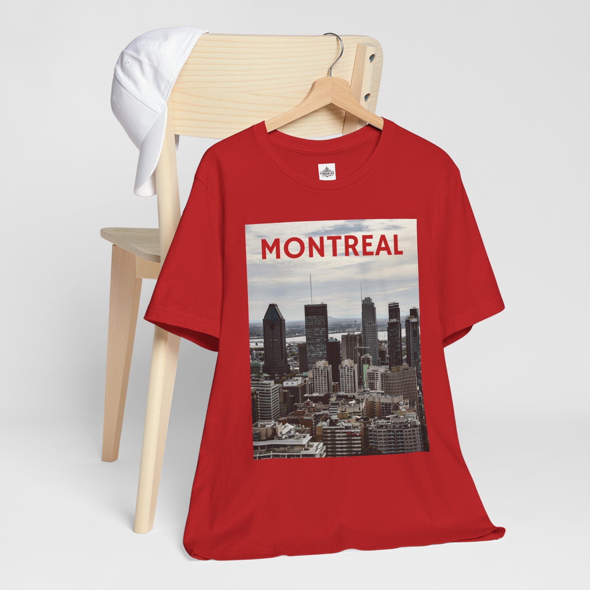 Red t-shirt with Montreal skyline graphic on a wooden chair against a white background